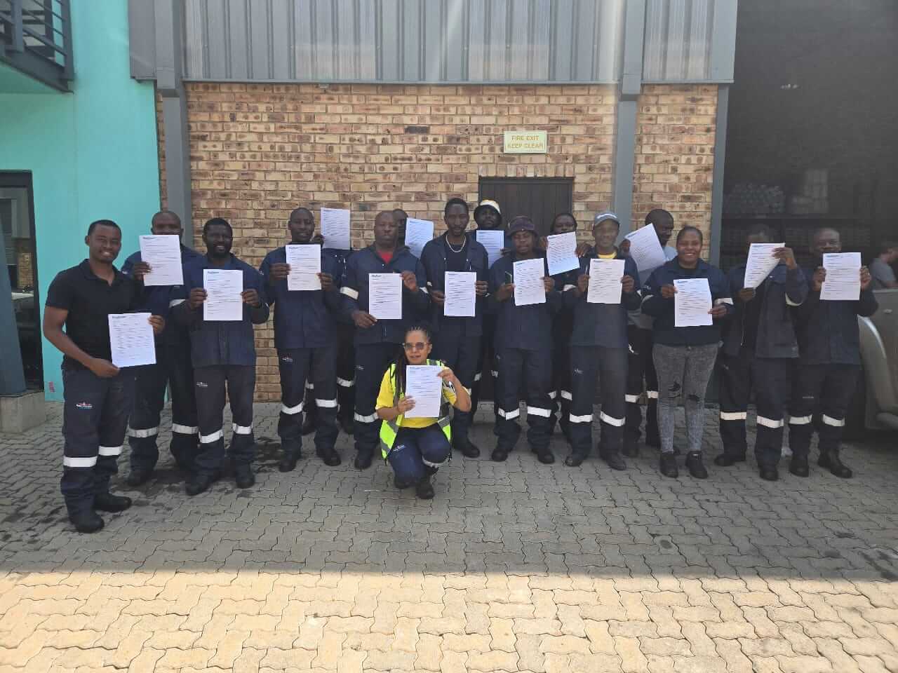 Group Of Workers Holding Certificates Outside Industrial Building. (1)