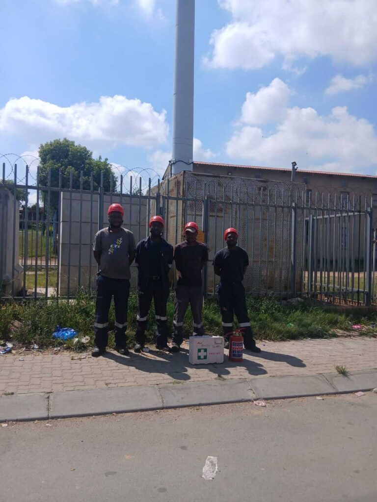 Group Of Workers Standing Outdoors Near Fenced Industrial Site. (1)